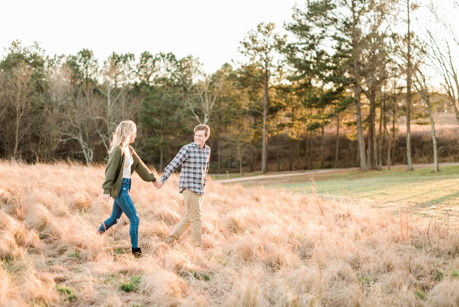 Raleigh couple with him holding her hand leading her down the grass hill photo
