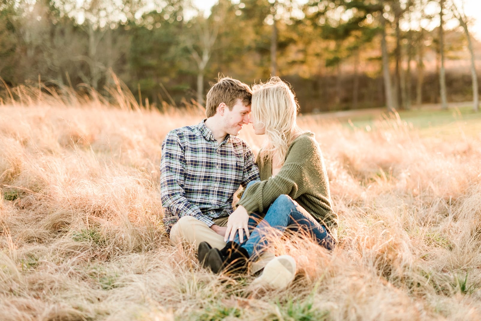 Raleigh sunset engagement session with the couple sitting in the grass field photo