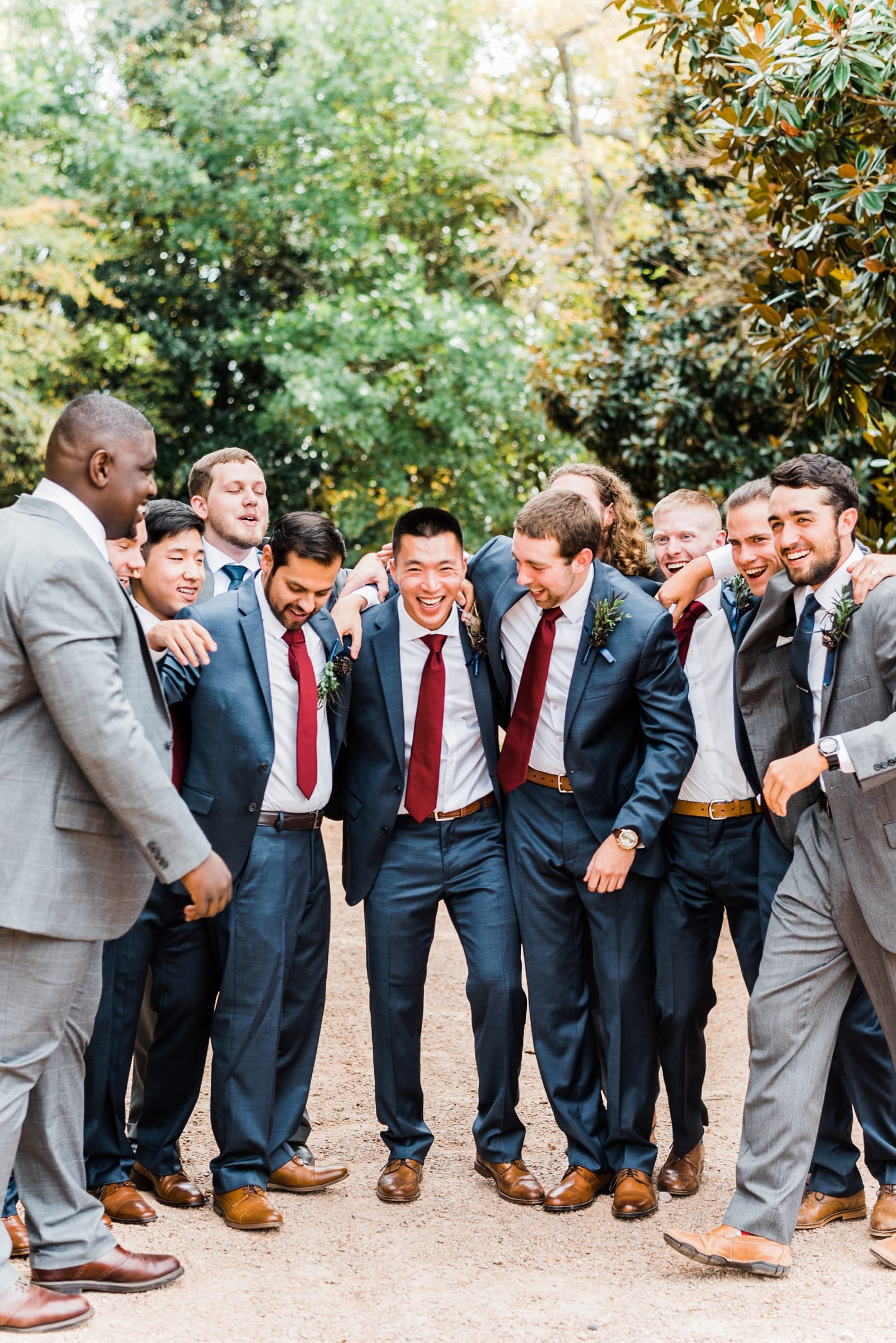 sutherland estate and garden wedding photographer groomsmen laughing navy suit grey suit groomsmen with burgundy tie photo