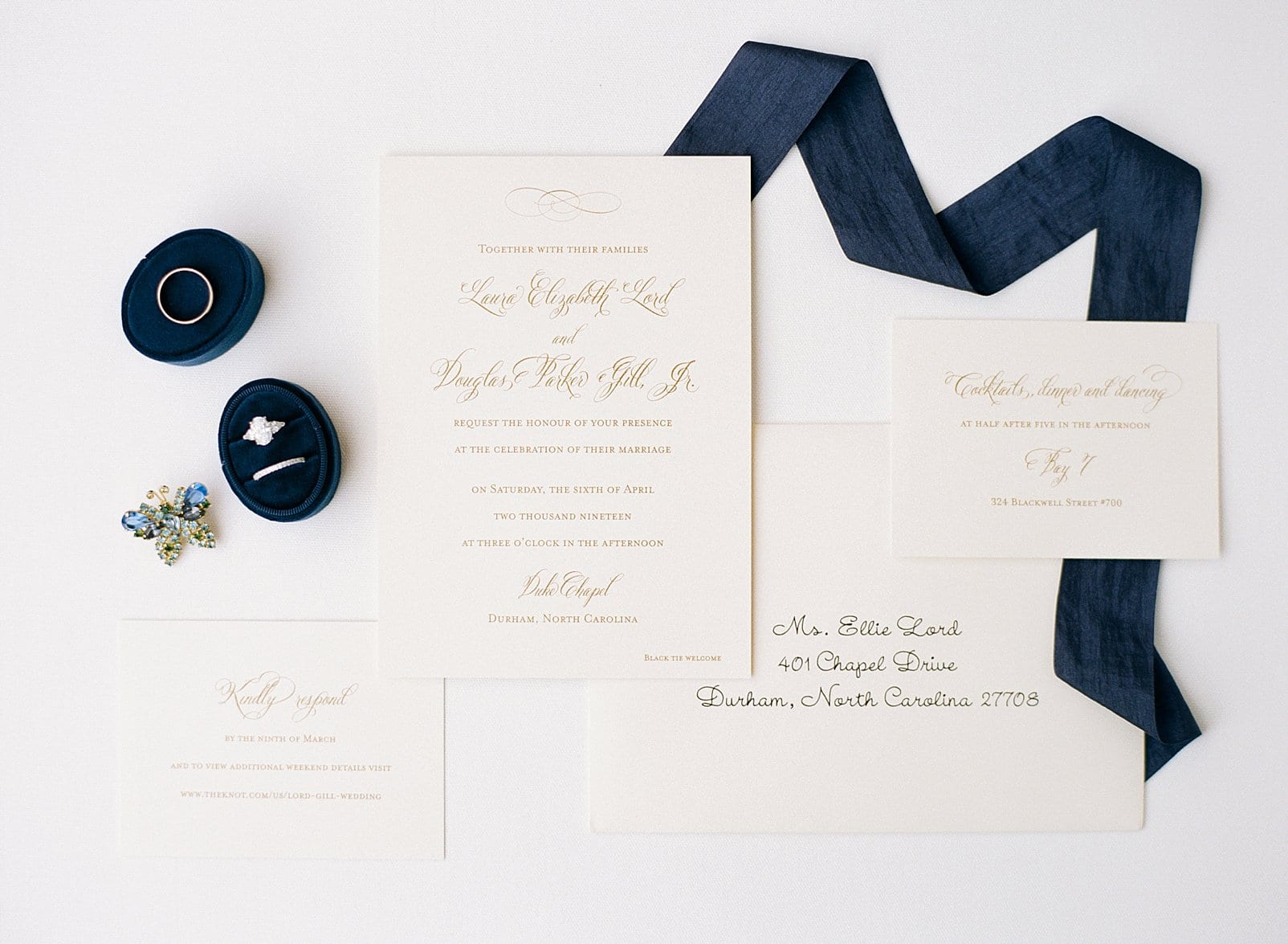 Reaves Engraving wedding invitation suite including cream paper with gold writing and navy blue ribbon photo