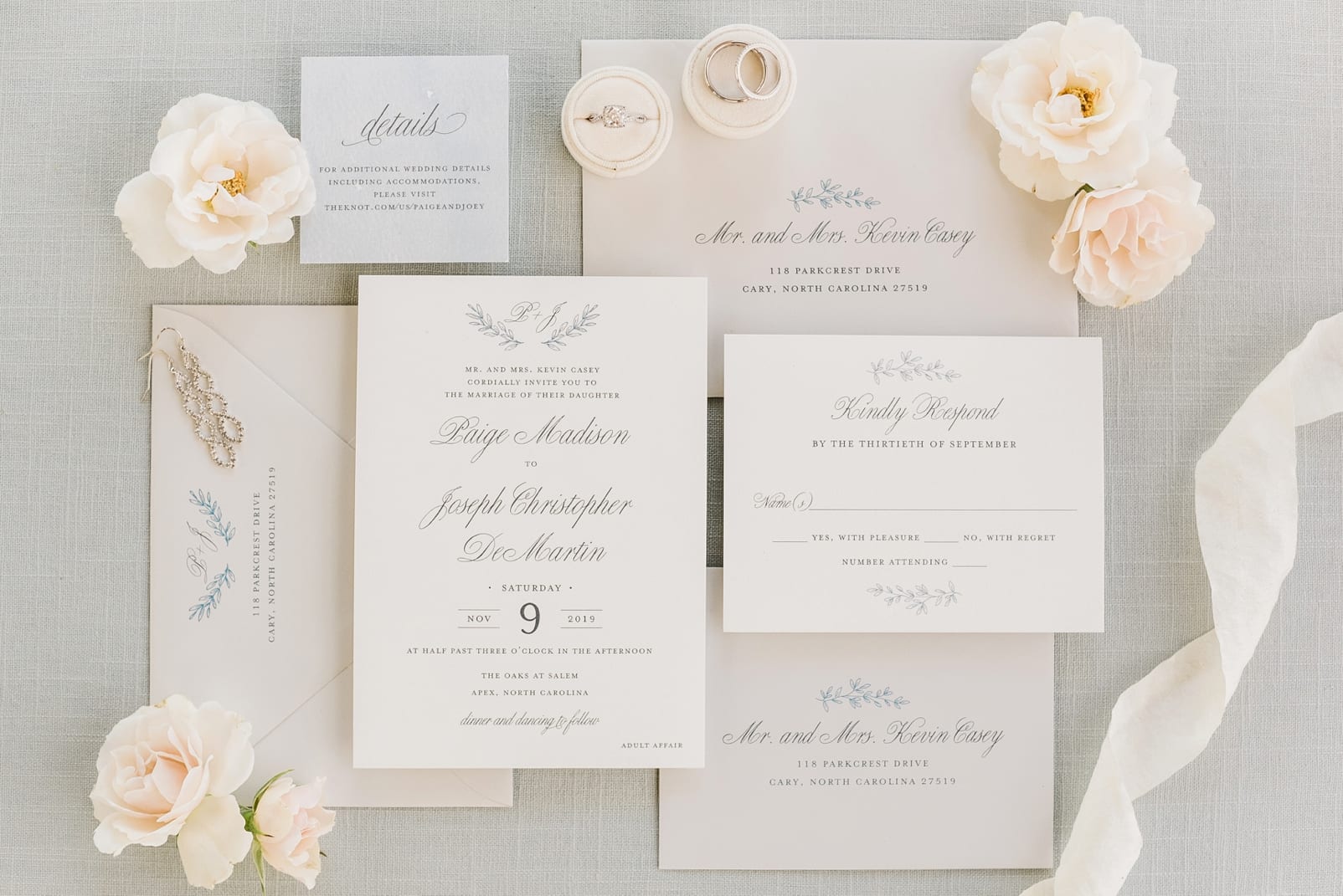 White wedding invitation suite styled with white flowers and blue script photo