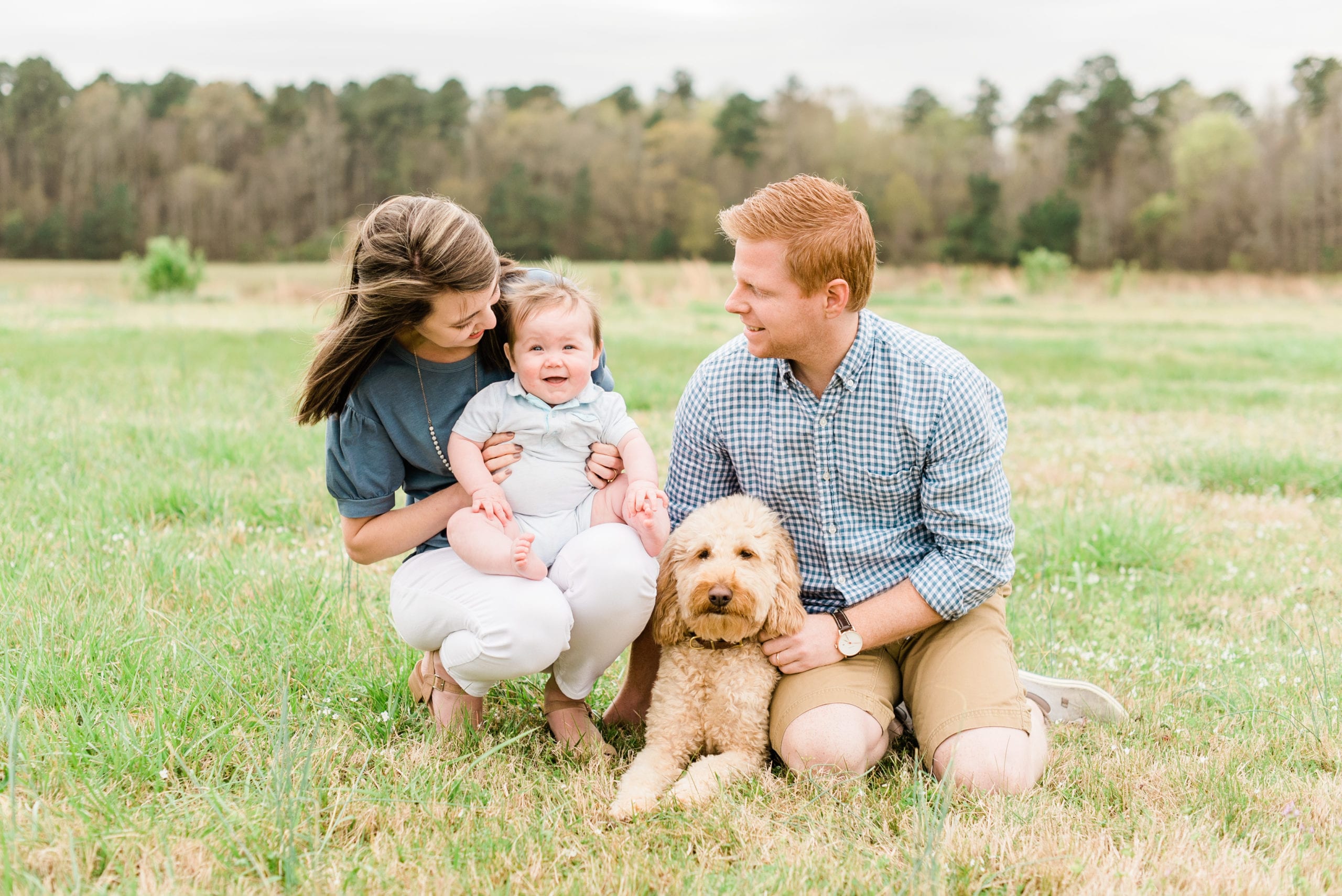 Wake Forest family with their 8 month old some in a light blue romper and their golden doodle puppy photo