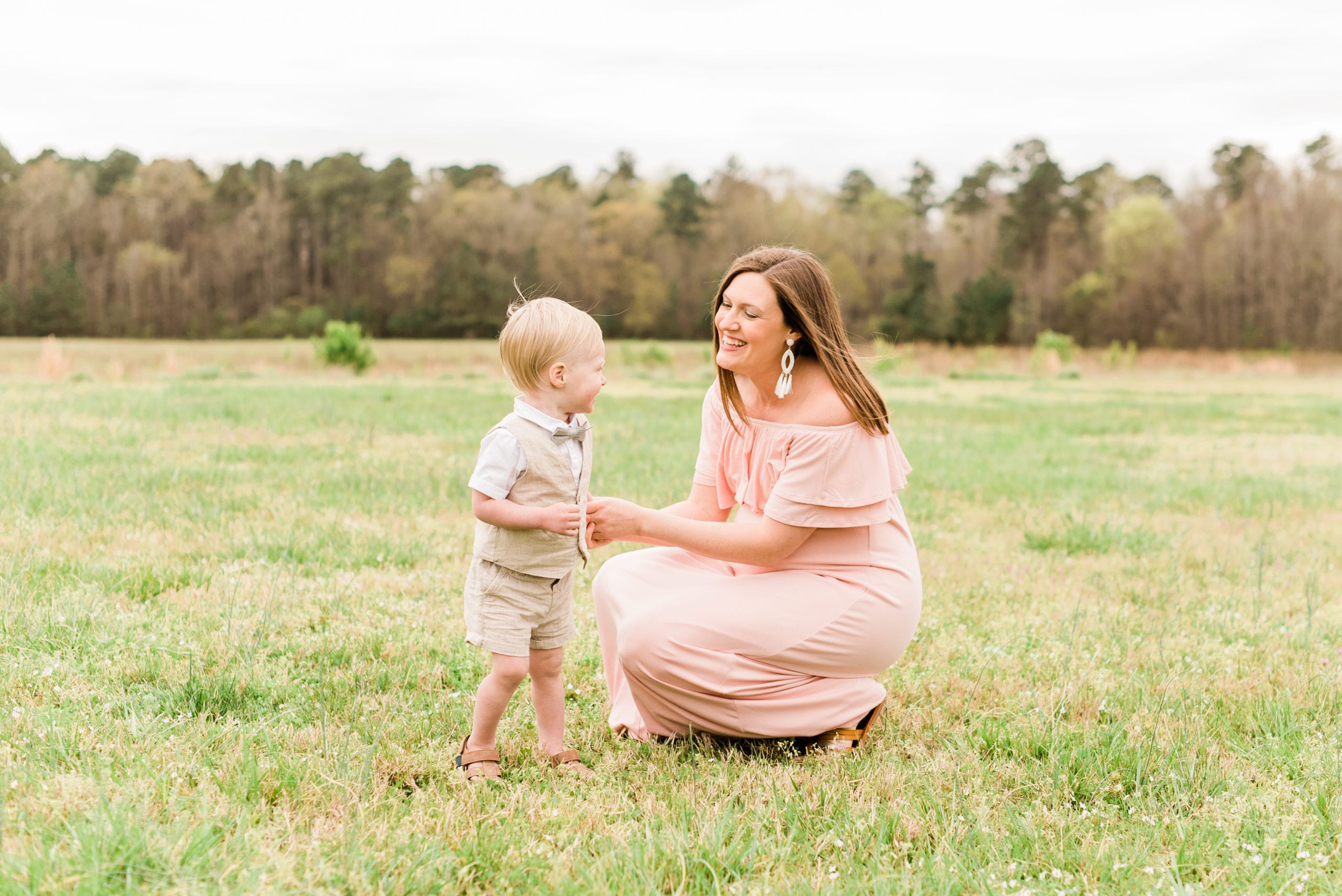 wake forest pregnant mother bending down to playing with her toddler son who is wearing a tan vest and bowtie photo