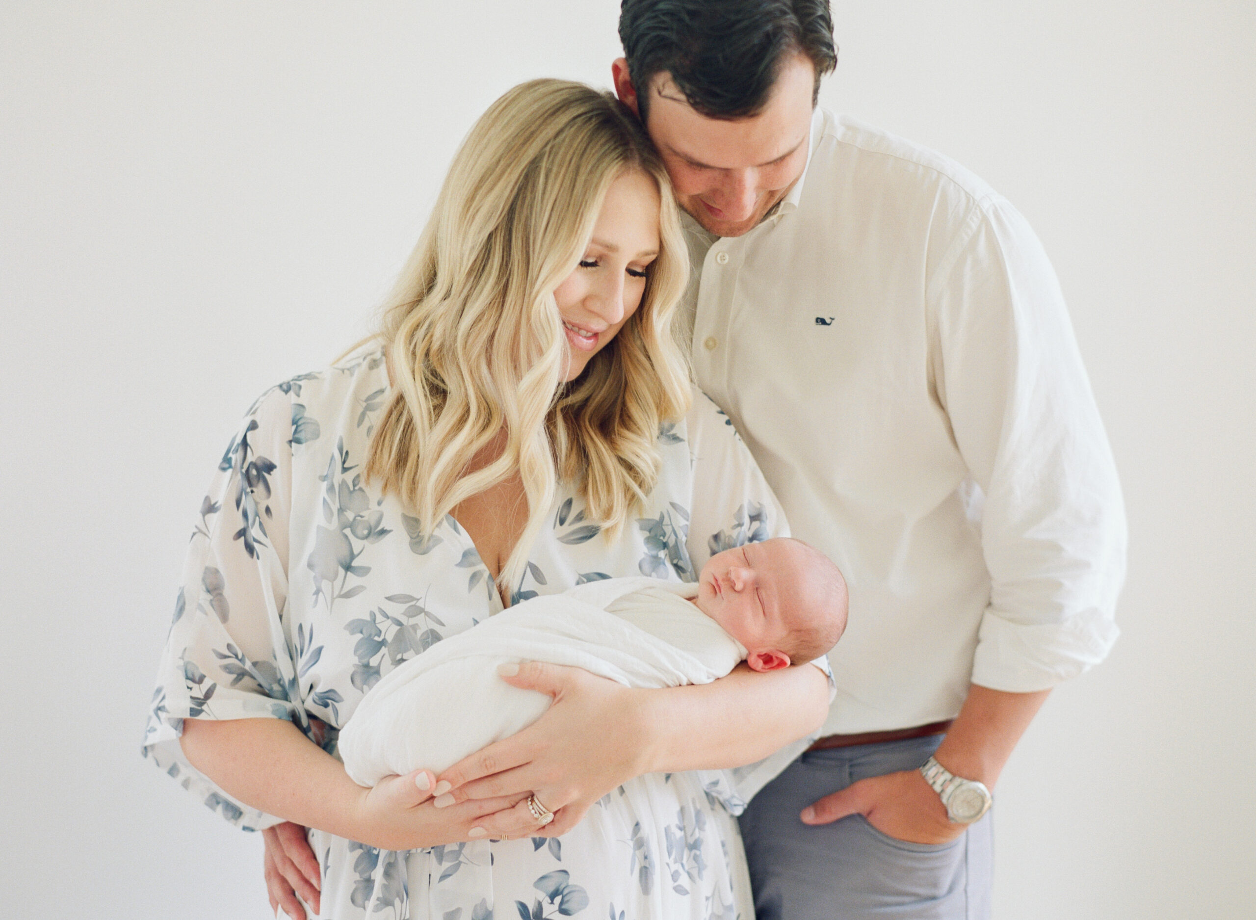 Mom and dad hold their newborn son while looking down lovingly over him during their Raleigh newborn session. Photographed by Raleigh Newborn Photographer A.J. Dunlap Photography
