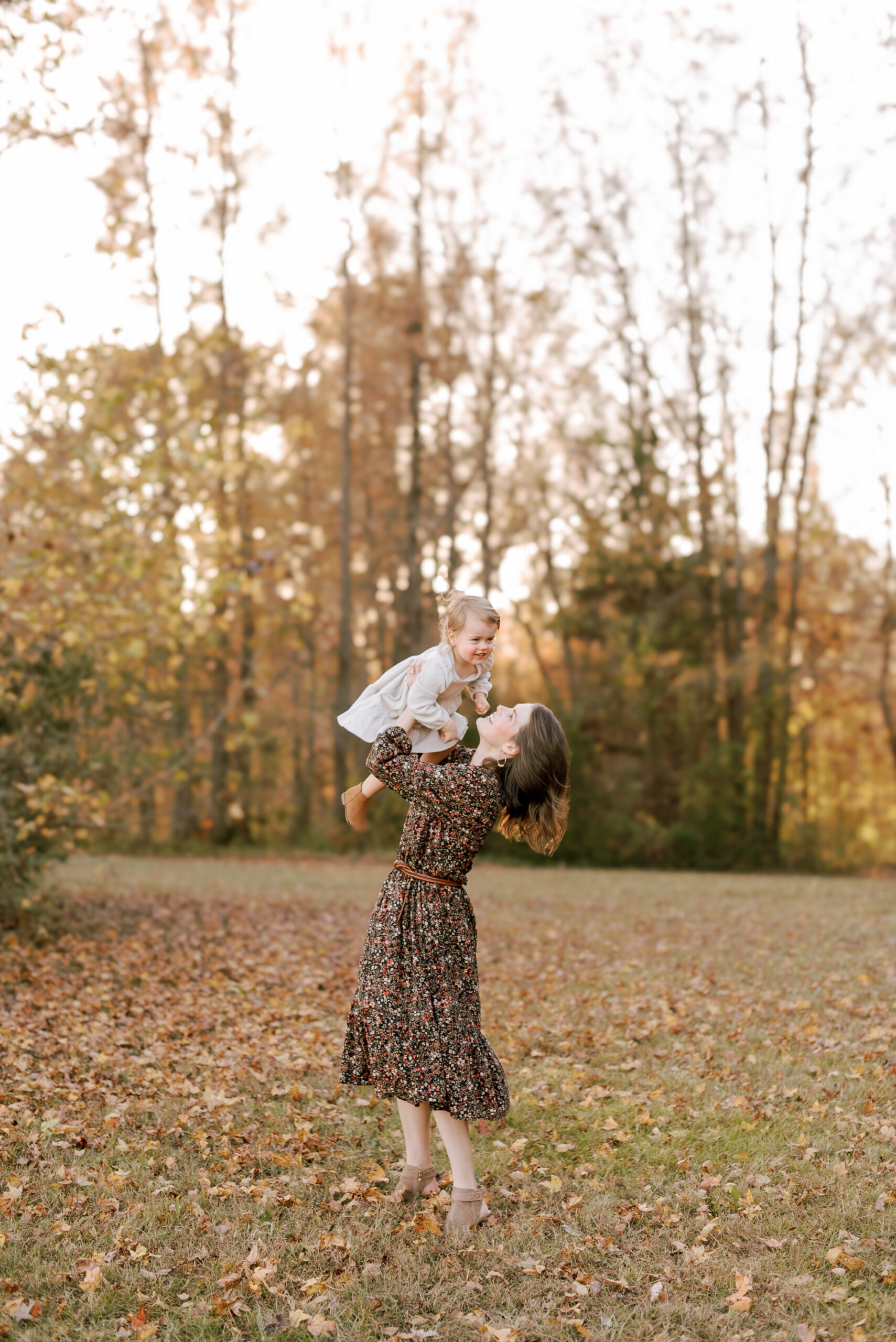 Mom plays with baby in the leaves at Horseshoe Farm Nature Preserve during their fall family portrait session. Image by Raleigh family photographer A.J. Dunlap Photography.