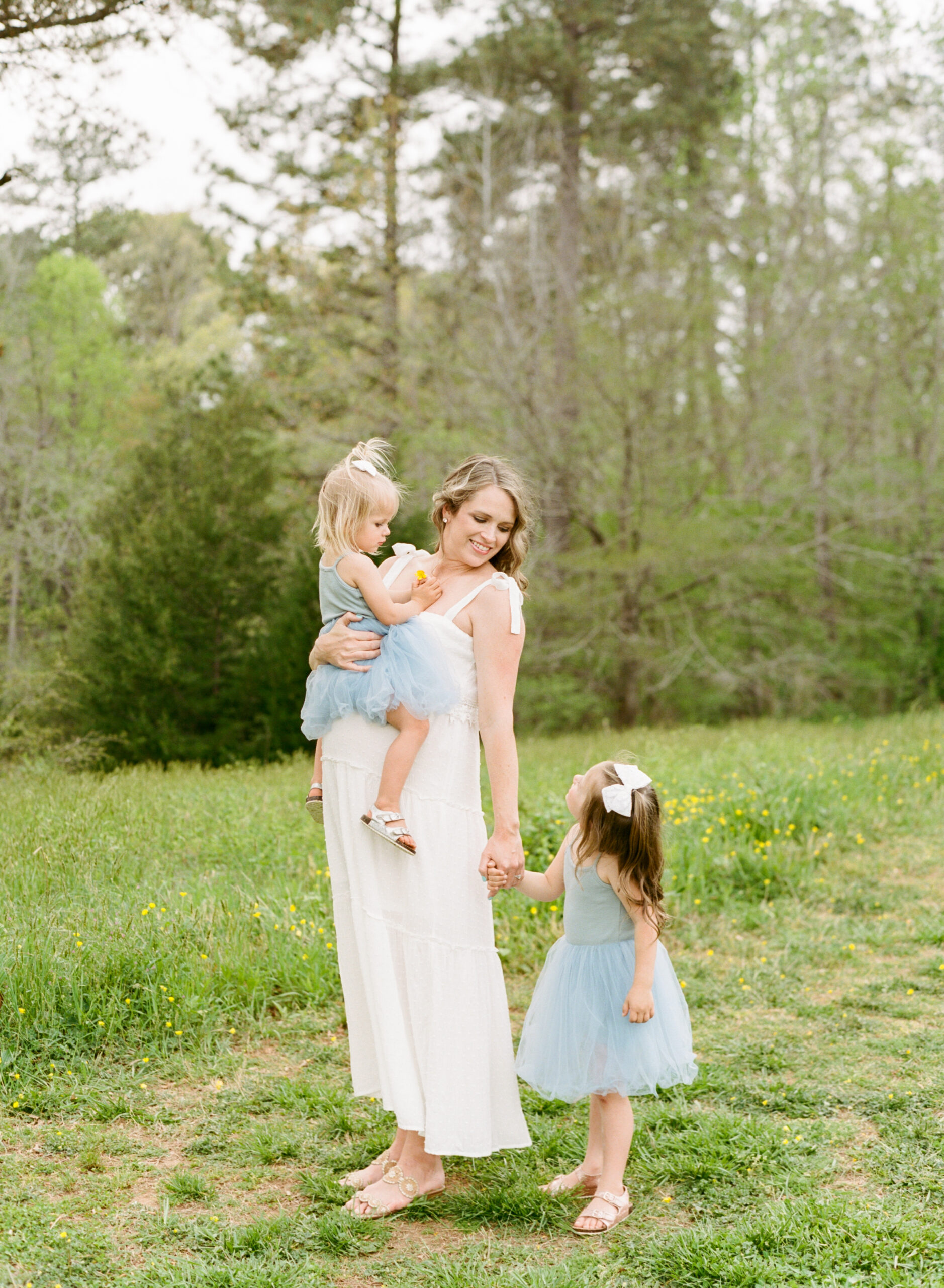 Pregnant mom plays with her daughters in a field. Photographed during Maternity Pictures Raleigh NC by A.J. Dunlap Photography.