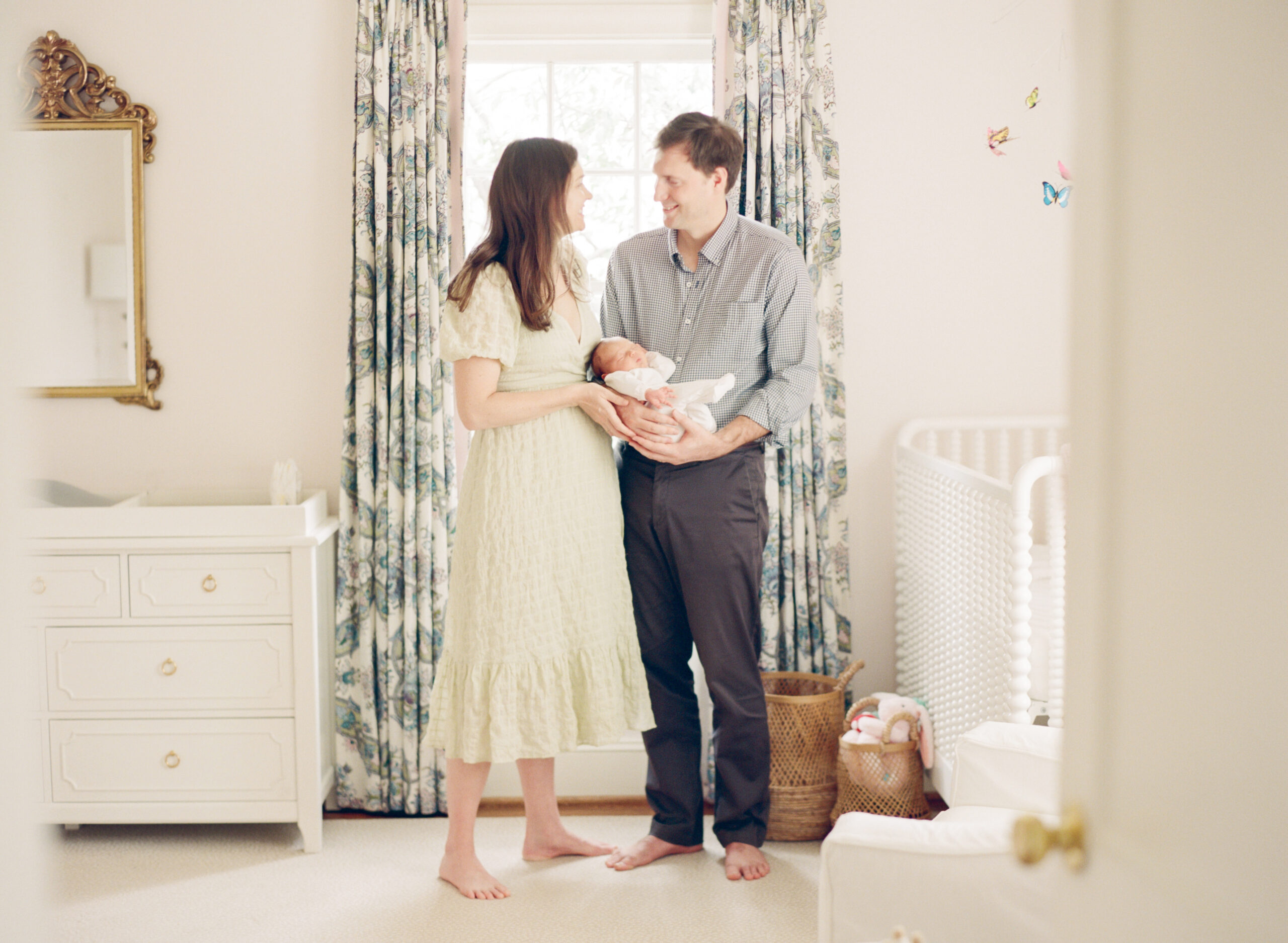 New parents smile at each other while holding their newborn daughter during their Charlotte newborn session. Image by Charlotte newborn photographer A.J. Dunlap Photography.